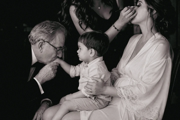 Bride and groom smiling together while holding a young child at their Abu Dhabi wedding.