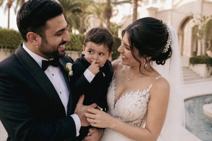 Bride and groom smiling together while holding a young child at their Abu Dhabi wedding.