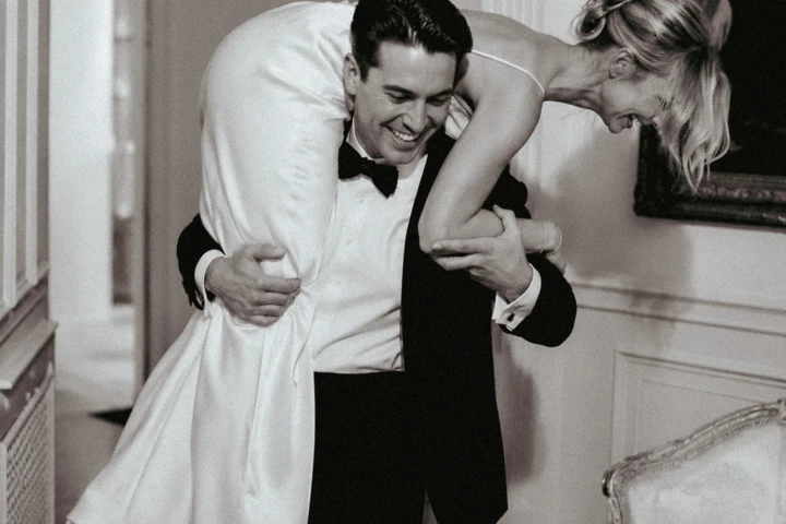 Laughing groom carrying the bride over his shoulder inside an Abu Dhabi wedding venue.