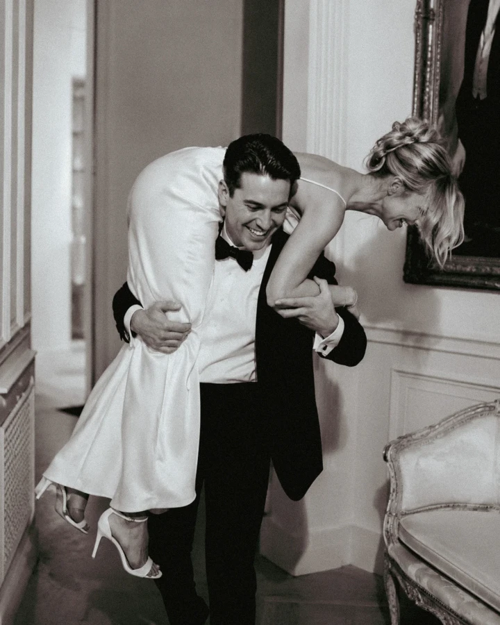 Laughing groom carrying the bride over his shoulder inside an Abu Dhabi wedding venue.