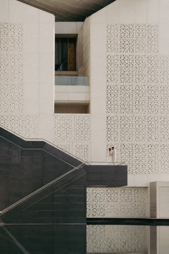 Bride and groom embracing beneath large geometric architectural walls in Abu Dhabi.