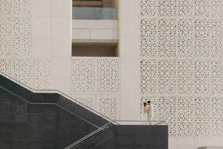 Bride and groom embracing beneath large geometric architectural walls in Abu Dhabi.