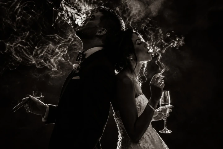 Bride and groom standing back-to-back with smoke illuminated around them during a creative wedding portrait in the UAE.