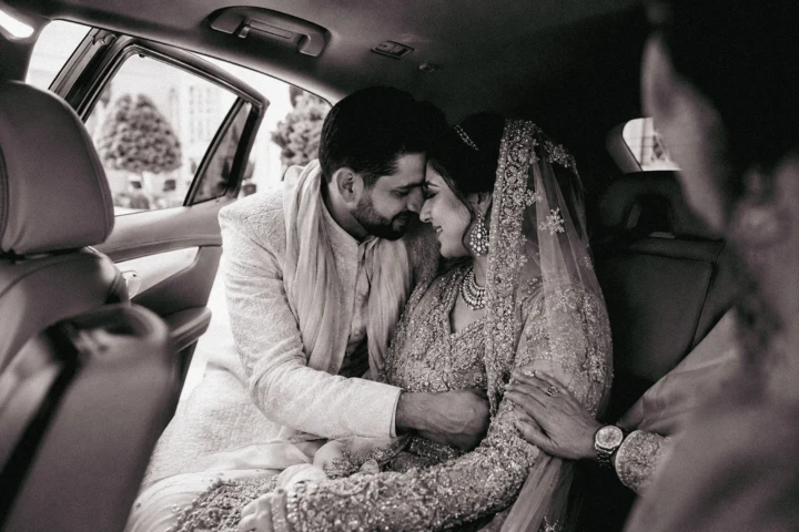 Afghan bride and groom touching foreheads inside a wedding car in Dubai
