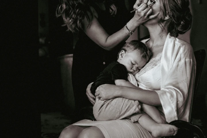Sleeping child resting on the bride’s lap while a makeup artist prepares her for a Dubai wedding.