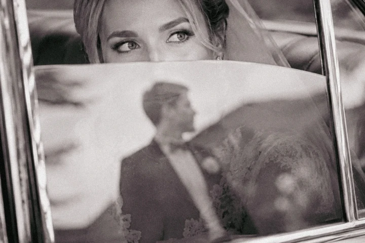 Bride looking through the window of a vintage wedding car during a luxury wedding in Dubai.