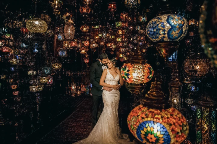 Iranian bride and groom embracing among colorful mosaic lanterns during a creative wedding portrait.