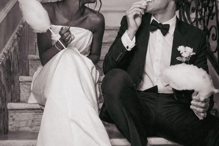 Bride and groom sitting on a staircase, laughing and eating cotton candy during their Istanbul wedding.