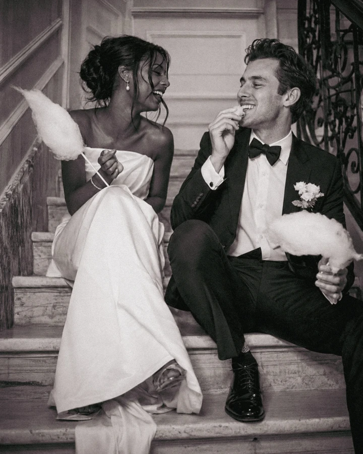 Bride and groom sitting on a staircase, laughing and eating cotton candy during their Istanbul wedding.