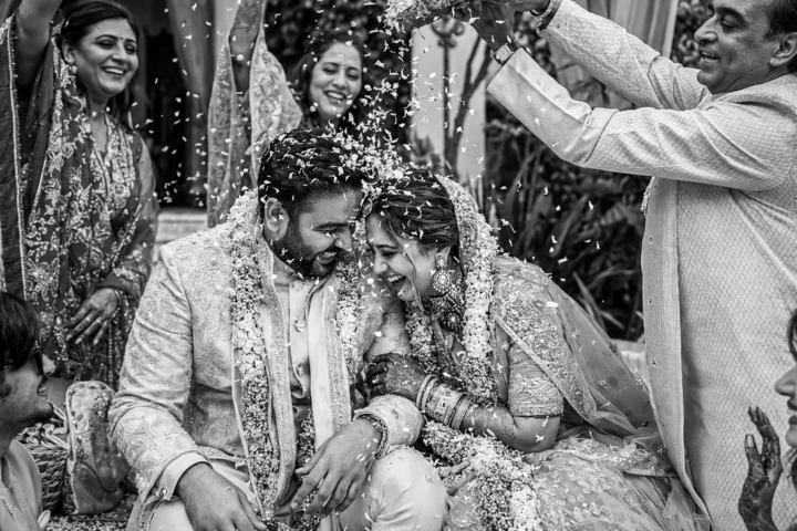 Indian bride and groom laughing while family members shower them with rice during a wedding ceremony in Dubai.