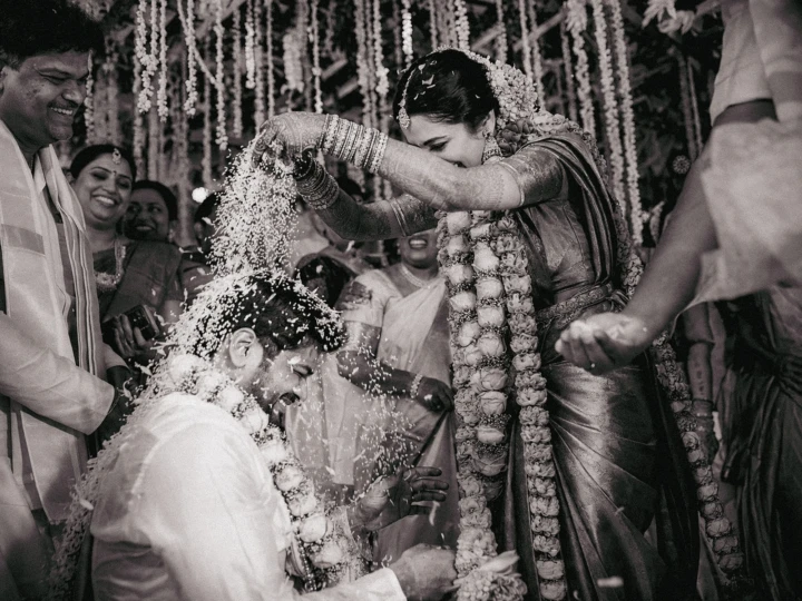 Indian bride pouring rice over the laughing groom during a traditional wedding ritual in Dubai.
