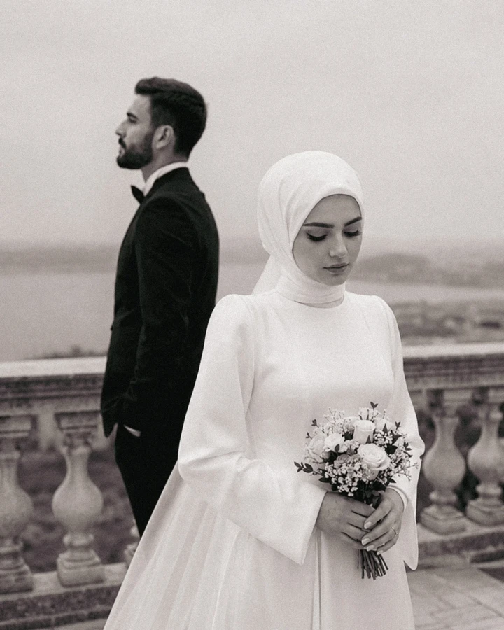 Bride and groom in the foreground with family members reflected in a mirror during a Muslim wedding ceremony in the UAE.