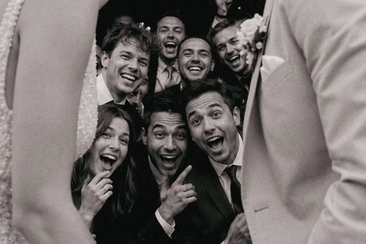 Bride and groom laughing together with excited wedding guests posing behind them during a celebration in Turkey.