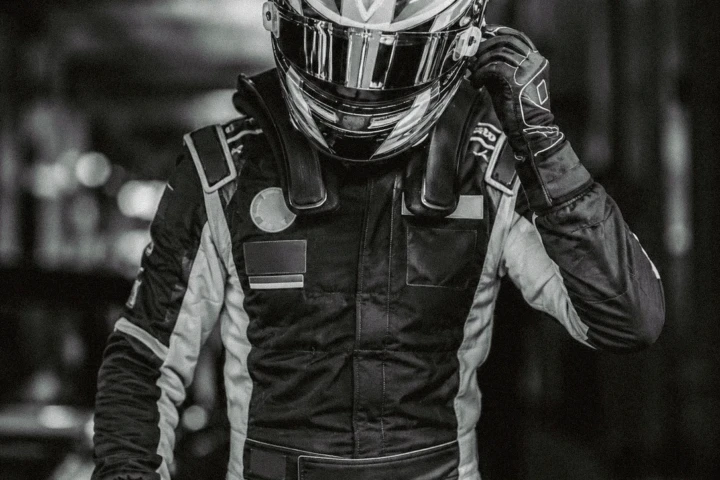 A professional racing driver adjusts his helmet before entering the track, captured in a dramatic black-and-white portrait for a motorsport photography portfolio serving Abu Dhabi, Dubai and the UAE.