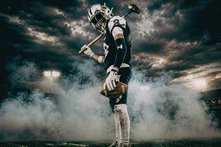 Dubai Sport Fitness Photography from American football player holding a football and sledgehammer in a smoky stadium