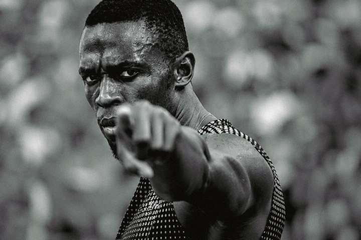 Close black-and-white portrait of a track athlete pointing toward the camera