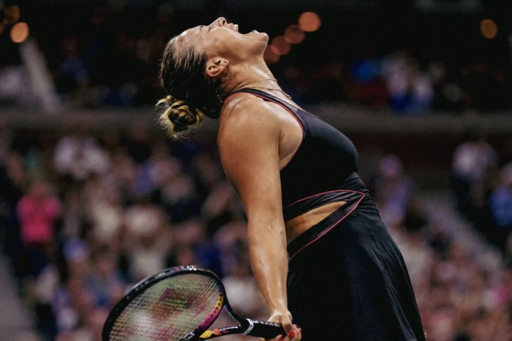 Female tennis player holding her racket and looking upward during an emotional match celebration