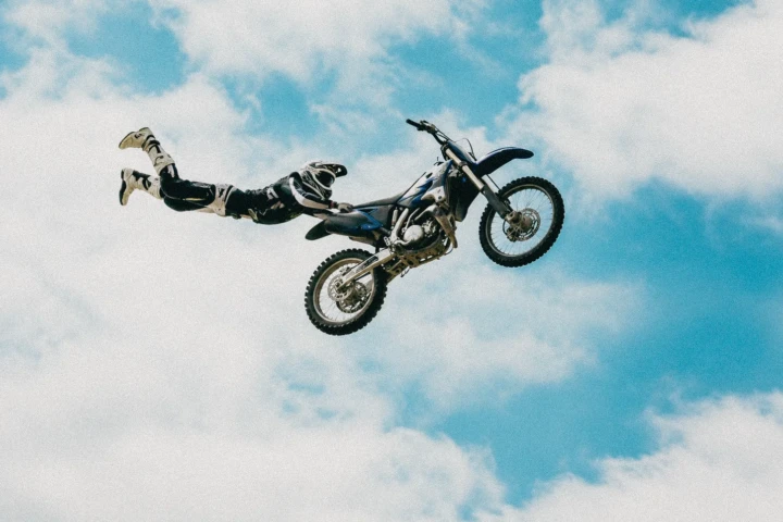 Freestyle motocross rider extending behind a dirt bike during an aerial Superman trick