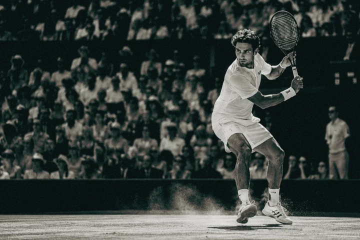 Male tennis player preparing a two-handed backhand during a stadium match in black and white