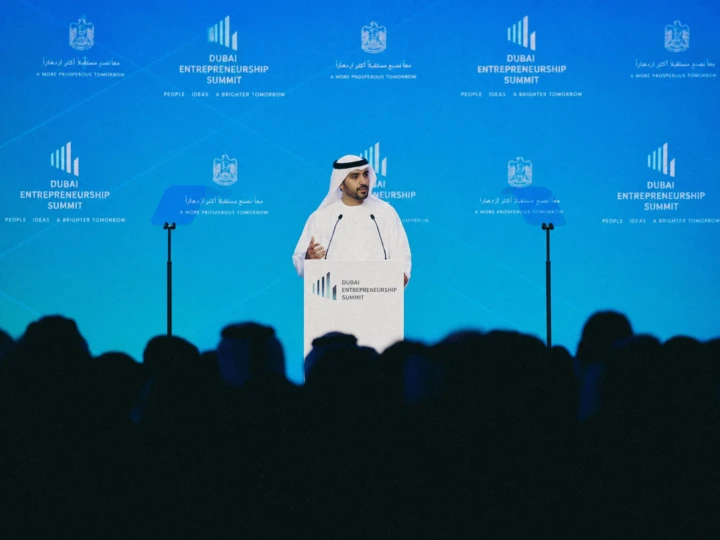Emirati speaker addressing the Dubai Entrepreneurship Summit from a branded lectern during professional business conference photography.