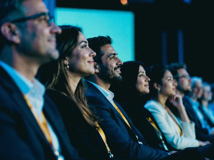 Conference audience watching a live presentation under blue stage lighting during professional corporate event coverage in Dubai and Abu Dhabi.