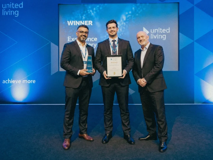 Corporate award winners posing with a trophy and certificate on a branded stage during professional event photography coverage for Dubai and Abu Dhabi.
