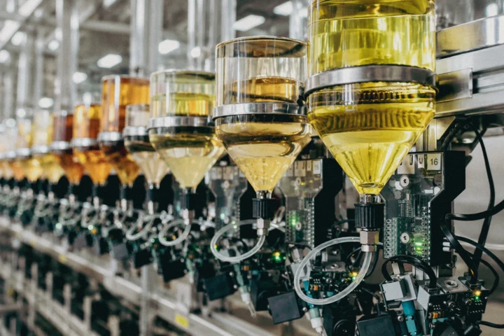 Automated liquid dosing and dispensing system with transparent reservoirs and industrial control components inside a manufacturing facility in Dubai, UAE.