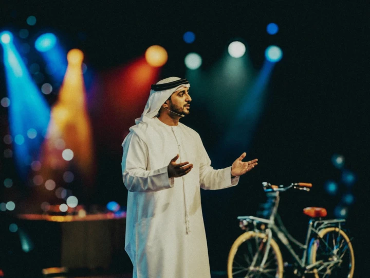 Emirati keynote speaker presenting on stage under colorful event lighting during professional conference photography coverage in Dubai and Abu Dhabi.
