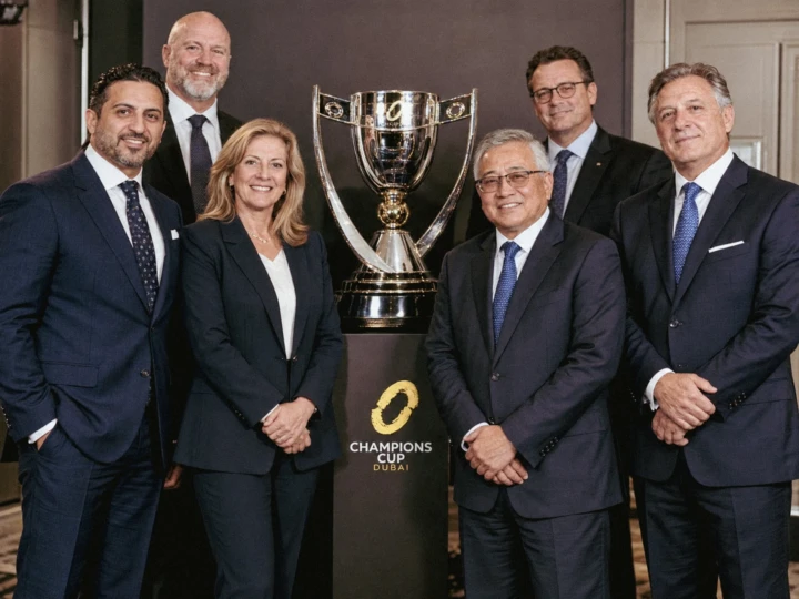 Business executives posing beside a championship trophy during a formal sports awards event in Dubai.