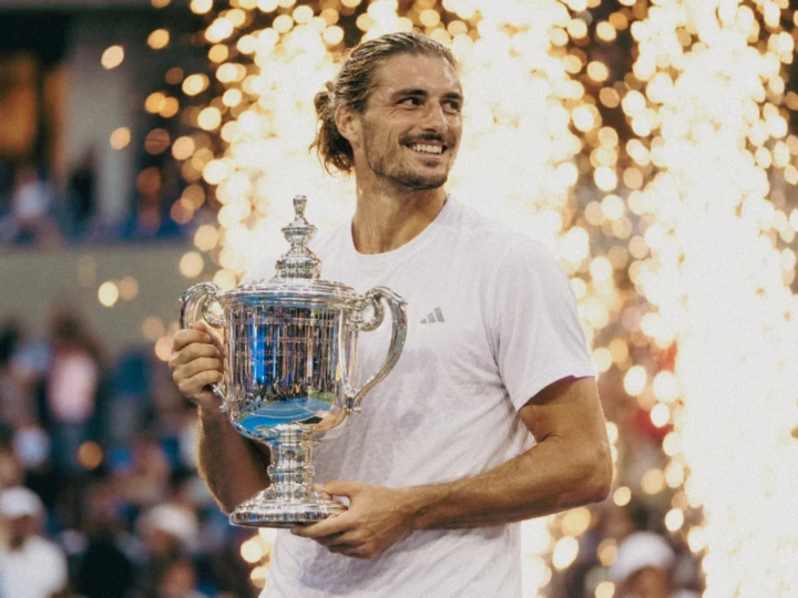 Athlete holding a championship trophy during a victory celebration with pyrotechnics at a professional sports event.