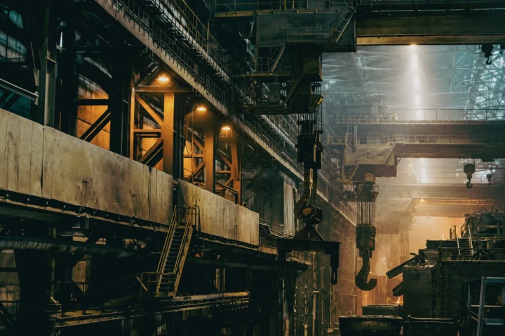 Interior of a heavy steel manufacturing facility with overhead cranes, lifting hooks and industrial production equipment photographed in Dubai, UAE.